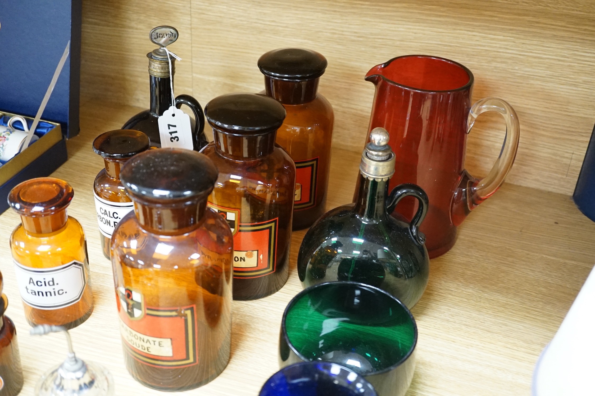 Nine glass chemist jars and covers, two decanters, two rinsers, and a cranberry jug and a mug, mostly coloured glass, jug 21 cams high